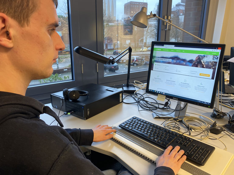 Blinder Nutzer am Computer, unter seiner Tastatur befindet sich eine Braillezeile
